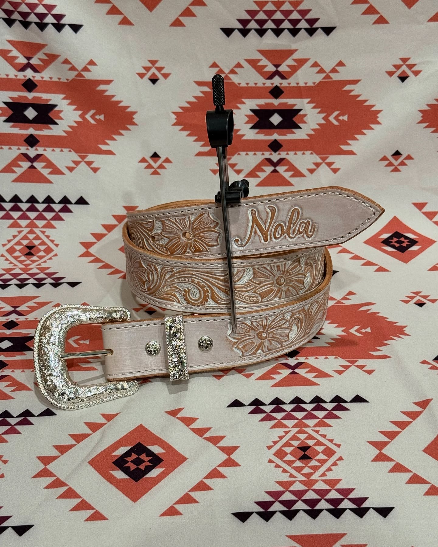 White tooled leather belt with Nola name and ornate silver buckle